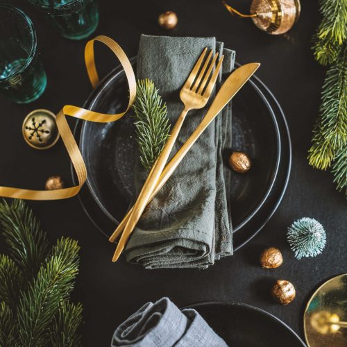 Served christmas table setting in dark tones with golden deco.
